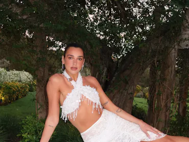 Dua Lipa lounging on her side in a white two-piece set