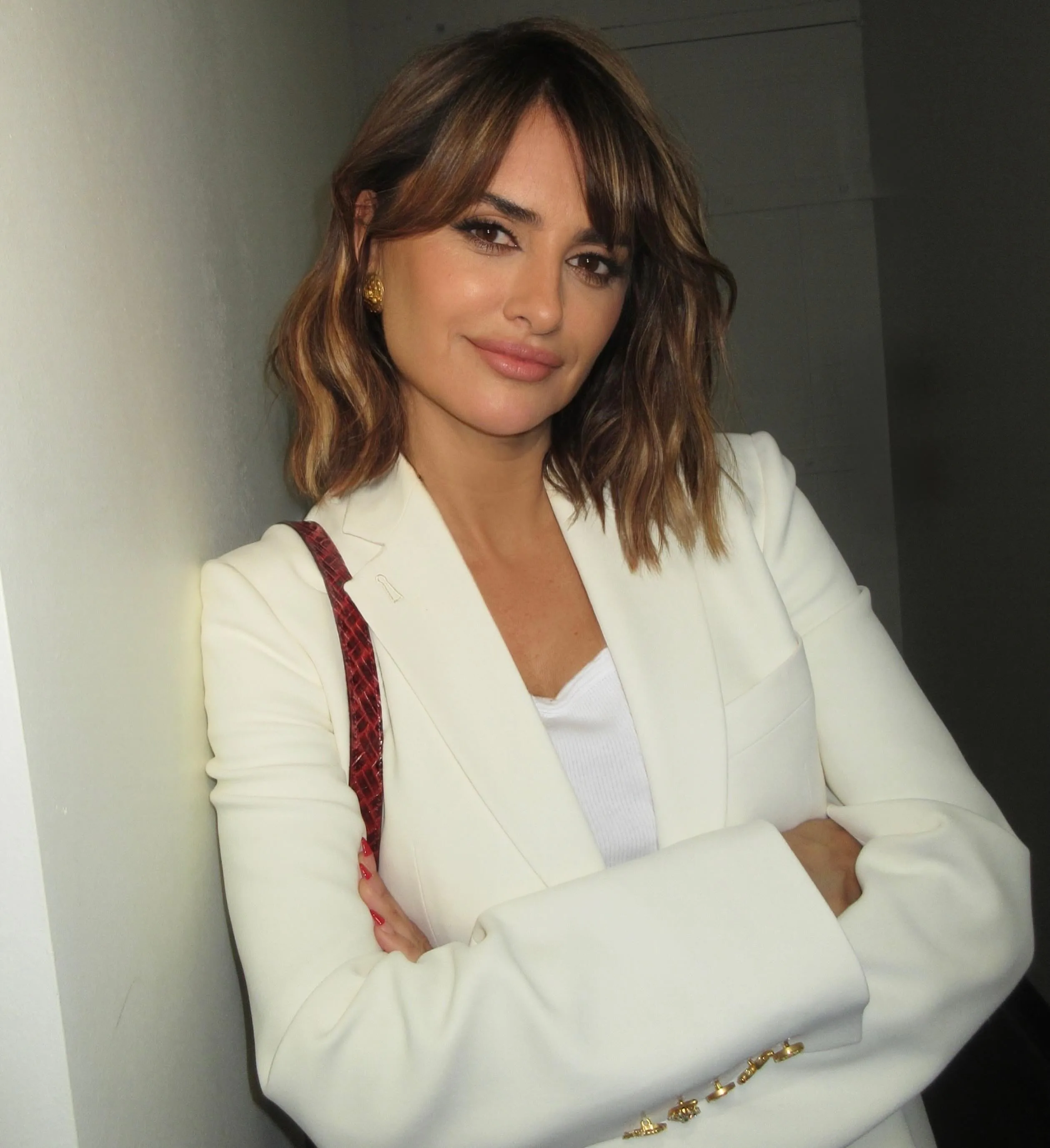 Penelope Cruz with a long french bob, standing against a wall