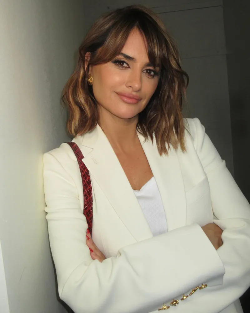 Penelope Cruz with a long french bob, standing against a wall