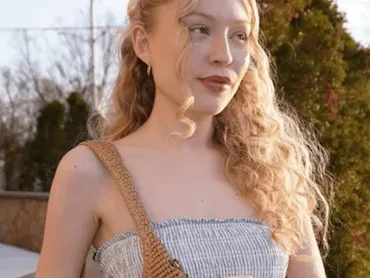 Woman with wavy blond hair holding Coach Brooklyn bag.