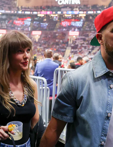 Taylor Swift holding Travis Kelce's hand and a cocktail.