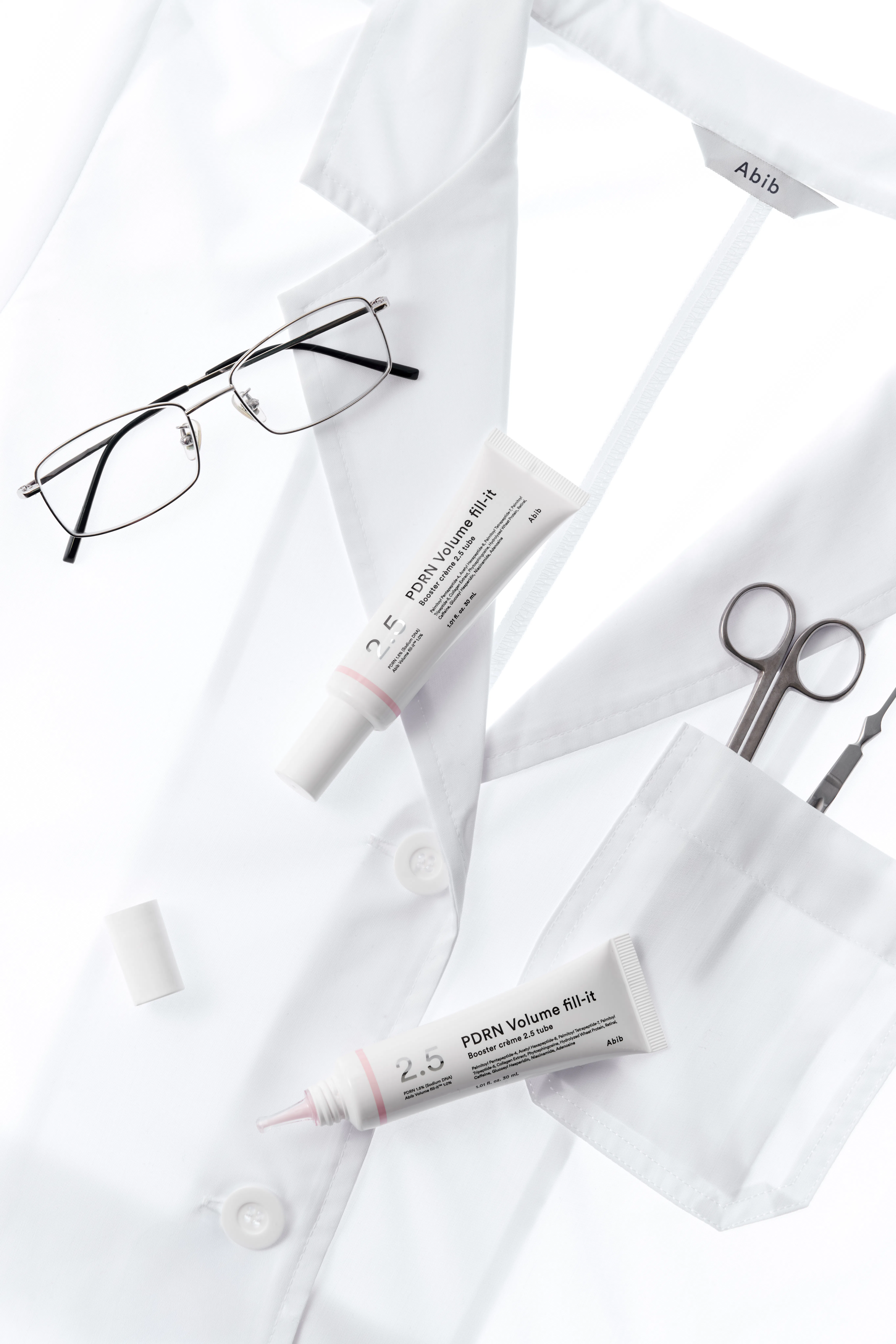 Two Abib PDRN Volume Fill-It Booster Creams against a white lab coat