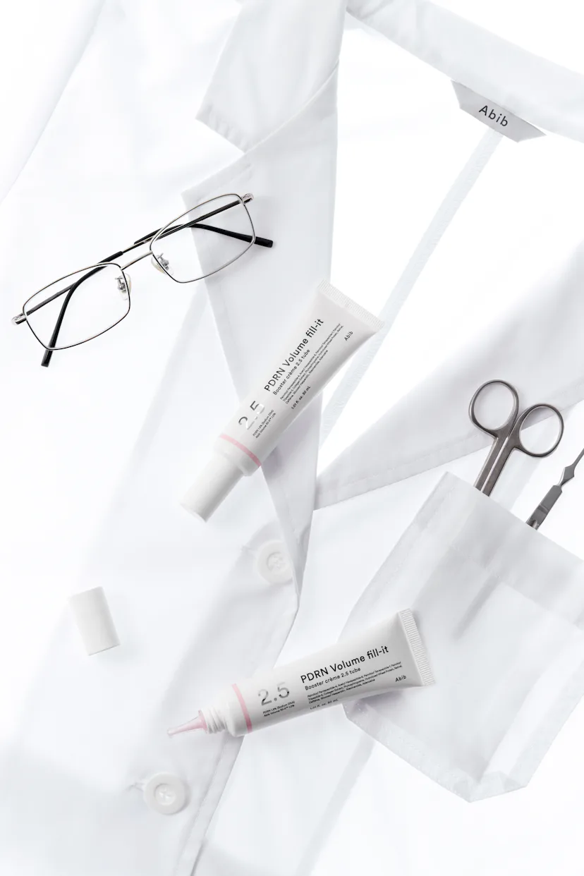 Two Abib PDRN Volume Fill-It Booster Creams against a white lab coat