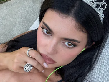 Kylie Jenner, wearing a tiara, her finger on her lip