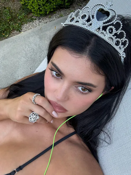 Kylie Jenner, wearing a tiara, her finger on her lip