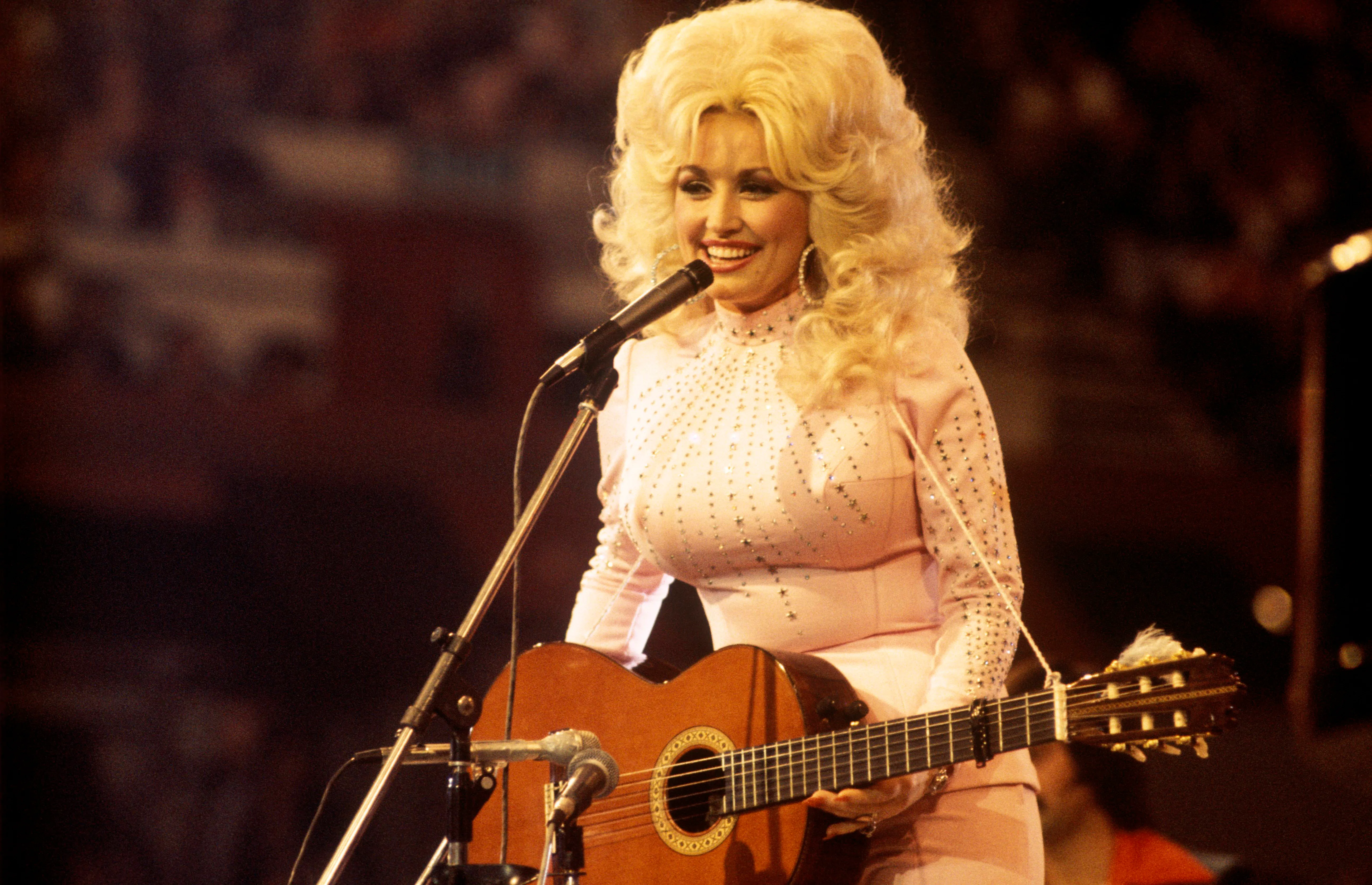 UNITED KINGDOM: American singer, songwriter and actress Dolly Parton, performs with a guitar, 1976.