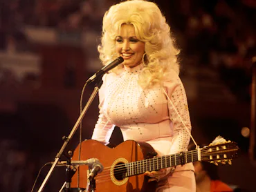 UNITED KINGDOM: American singer, songwriter and actress Dolly Parton, performs with a guitar, 1976.