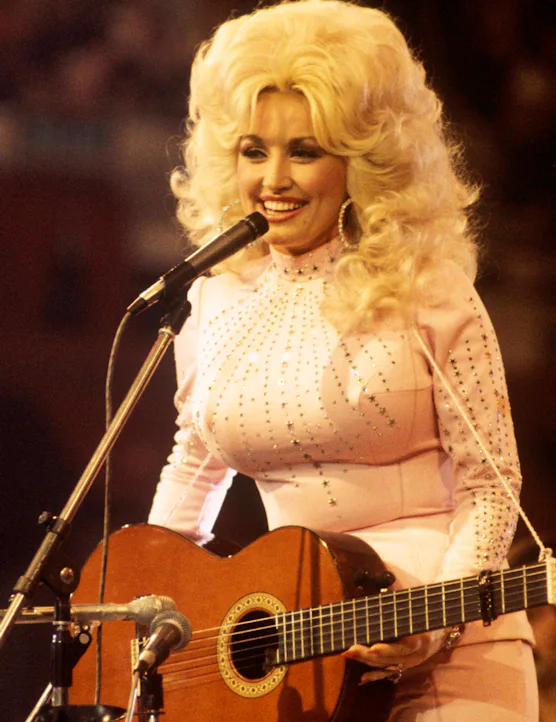 UNITED KINGDOM: American singer, songwriter and actress Dolly Parton, performs with a guitar, 1976.