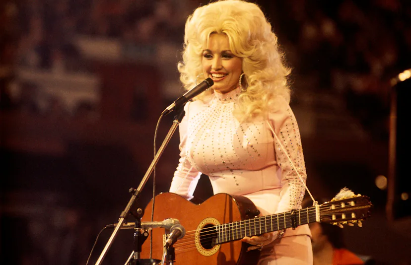 UNITED KINGDOM: American singer, songwriter and actress Dolly Parton, performs with a guitar, 1976.