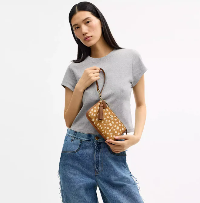 A model holding the Coach Nolita 19 bag as a wristlet