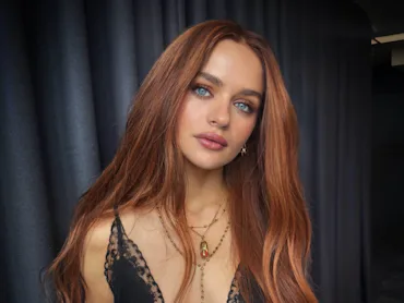 Joey King with long, straight red hair looking at the camera