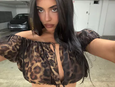 Kylie Jenner in a selfie, wearing an animal print top in a garage