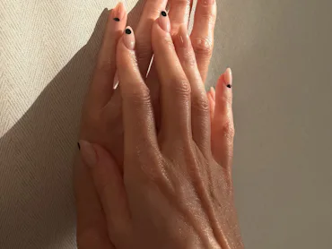 A nude manicure with black polka dots