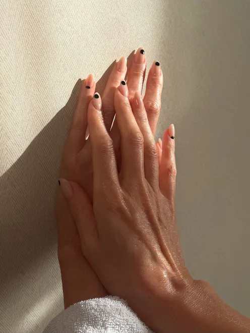 A nude manicure with black polka dots