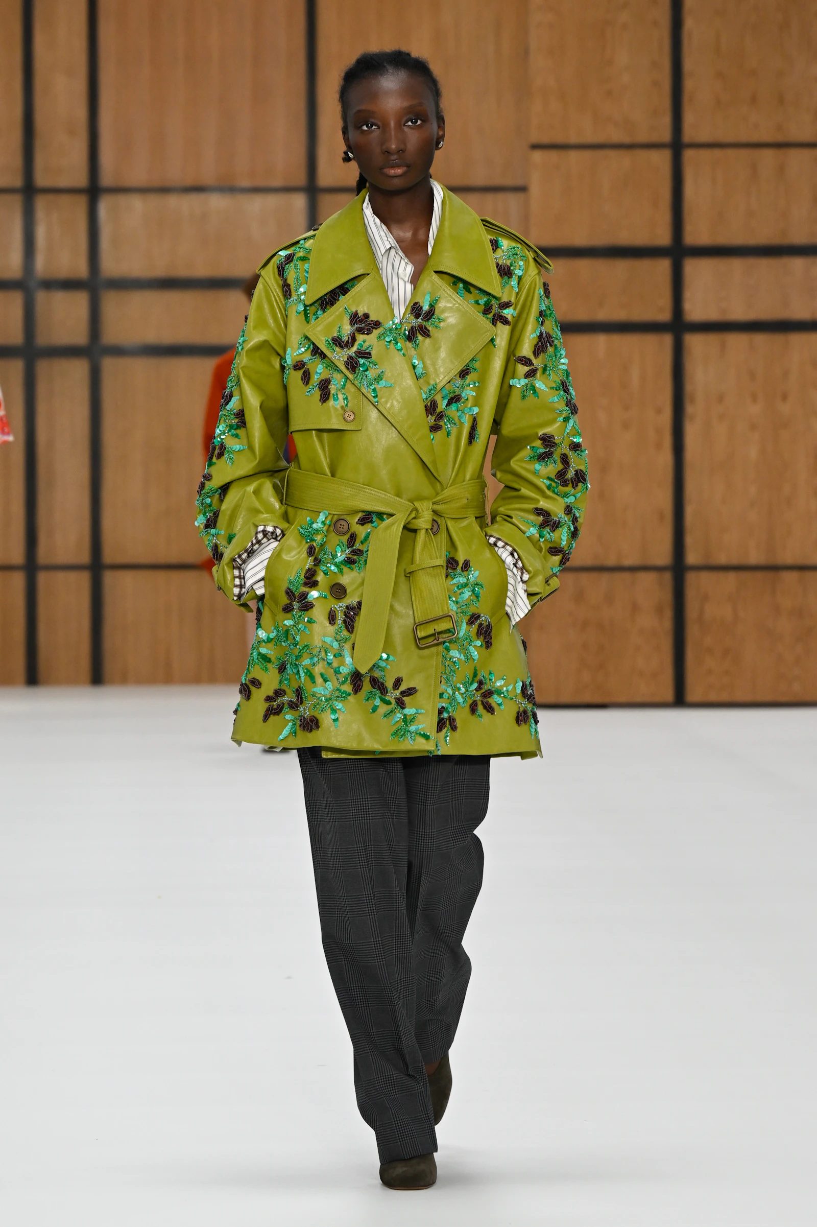 Model wearing an acid green Burberry trench embroidered with blue and purple flowers
