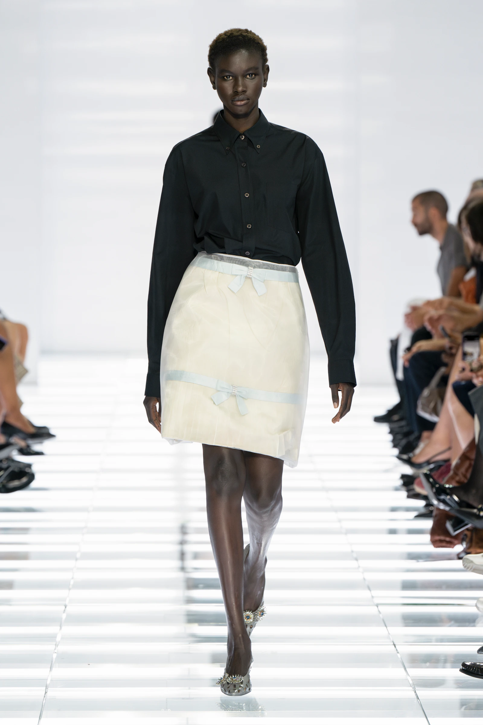 Model in a black Prada shirt and sculptural white skirt