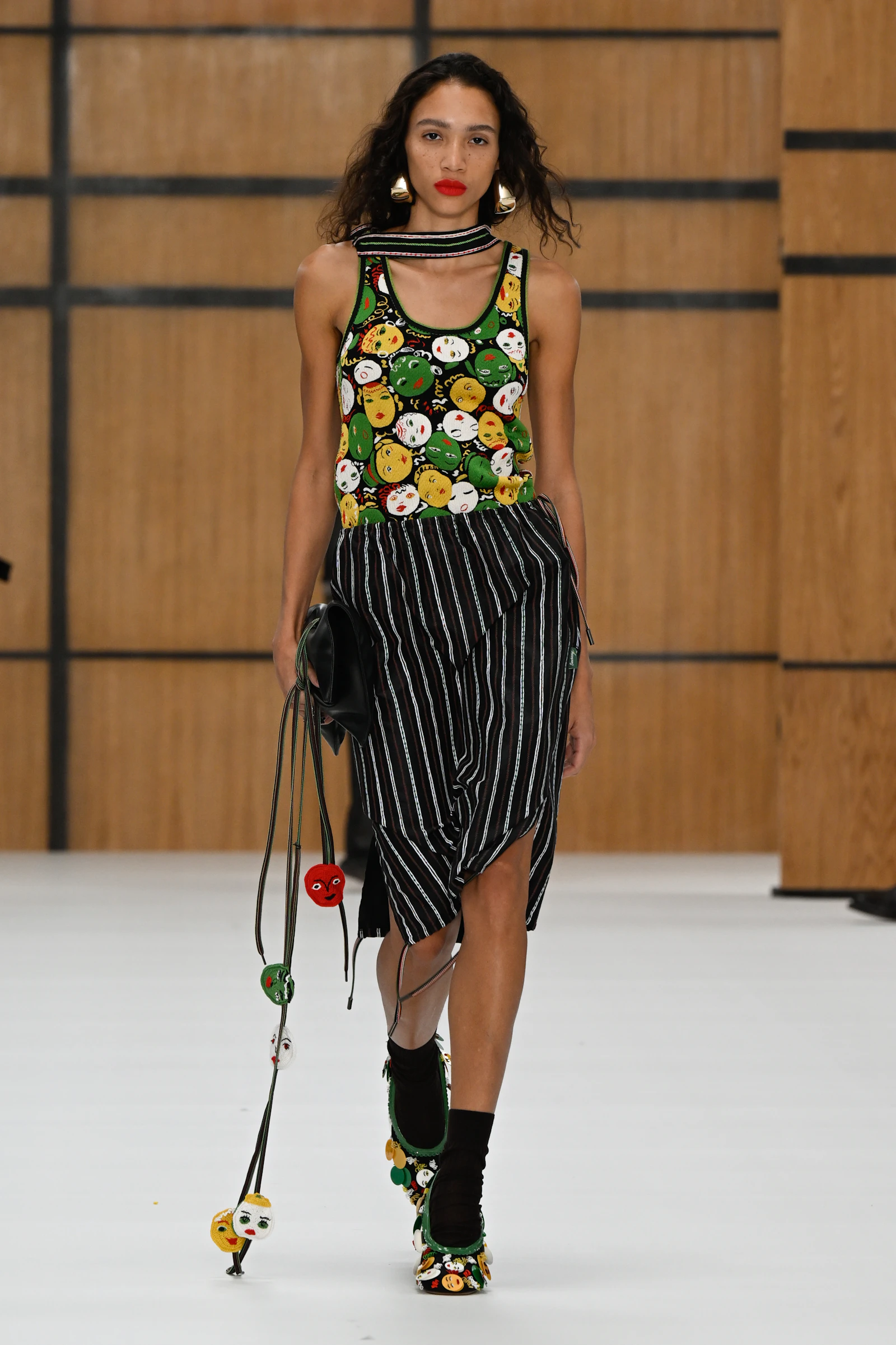 Model in a Burberry tank covered with colourful Celia Birtwell face motifs and a striped skirt