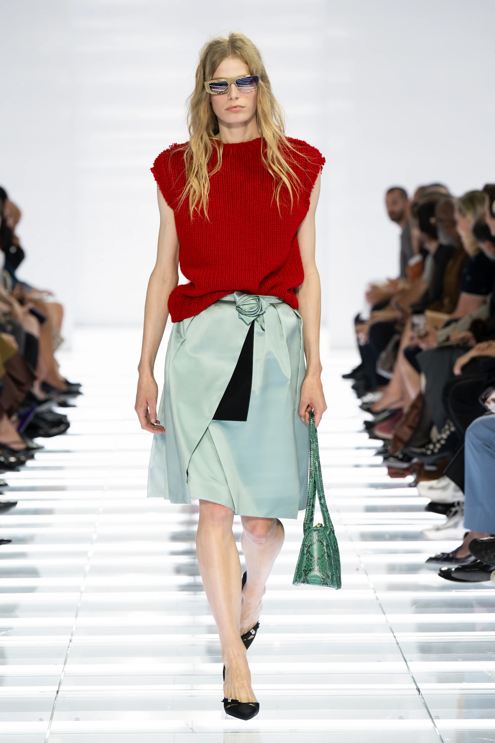 Model in a red Prada knit and pale aqua wrap skirt secured with a black fastening