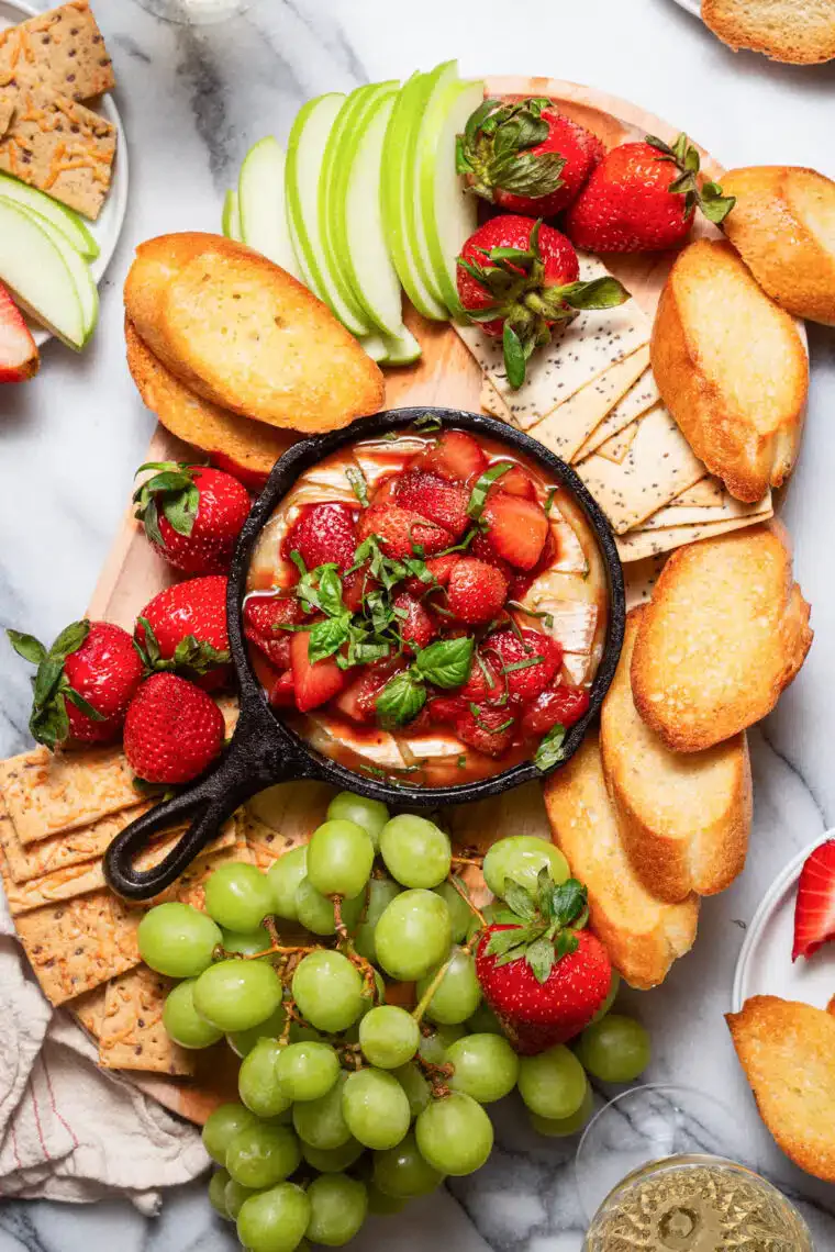 strawberry baked brie at the center of a charcuterie board, in a story about recipes to use up straw...