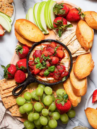 strawberry baked brie at the center of a charcuterie board, in a story about recipes to use up straw...