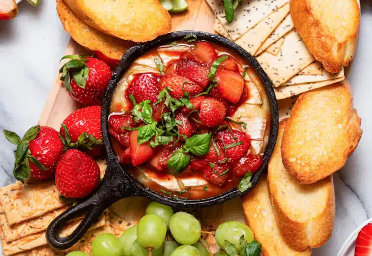 strawberry baked brie at the center of a charcuterie board, in a story about recipes to use up straw...