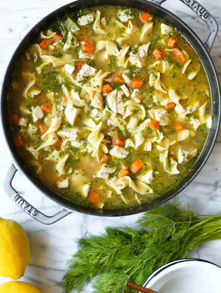 homemade chicken noodle soup in a staub pot, in a story about easy recipes for when you're sick