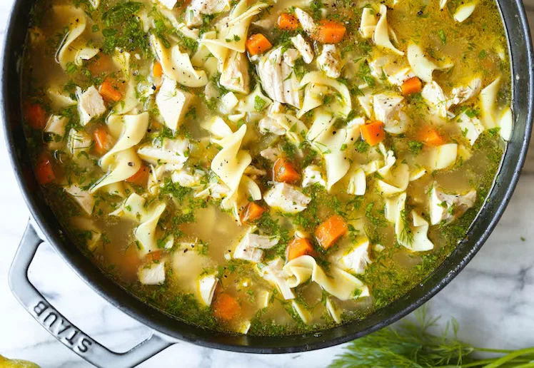 homemade chicken noodle soup in a staub pot, in a story about easy recipes for when you're sick