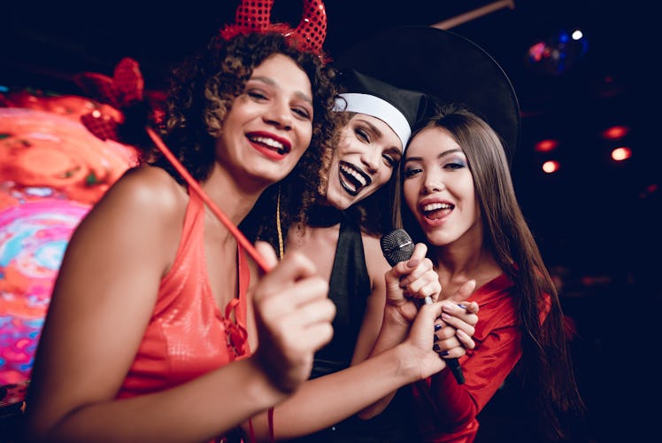 Halloween party. Three girls in sexy outfits kinoshnyh villains are posing in a nightclub. They sing...