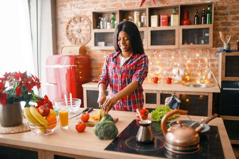 Black woman cooking healthy breakfast on kitchen. Personal factors that can influence food choices m...