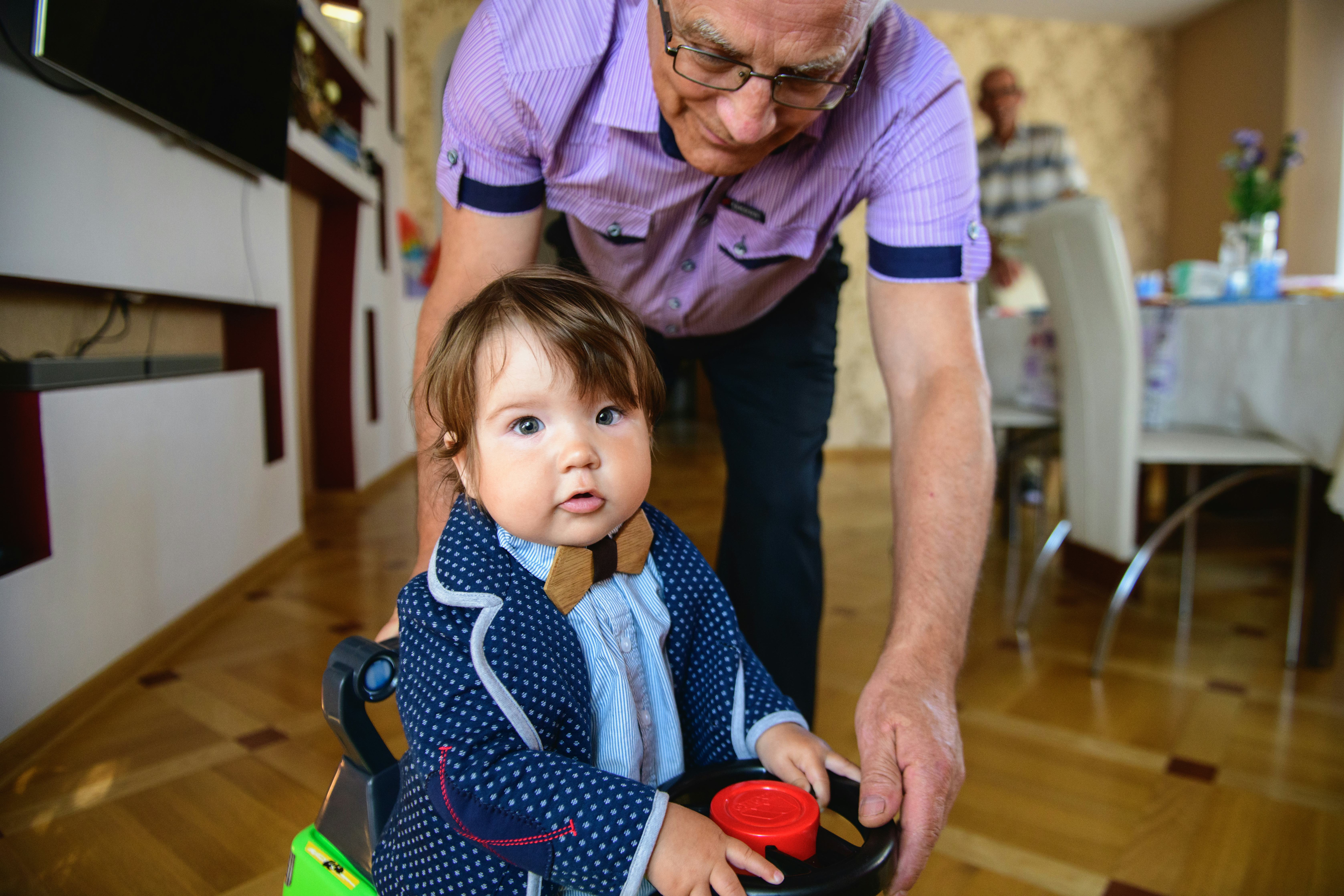 grandfather rolls grandson in a toy car. redirection of grandfather and grandson. Happy weekend conc...