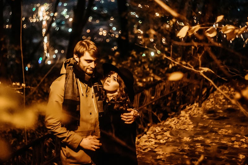 happy stylish couple hugging and holding hands with tender under yellow lantern  in night lights of ...