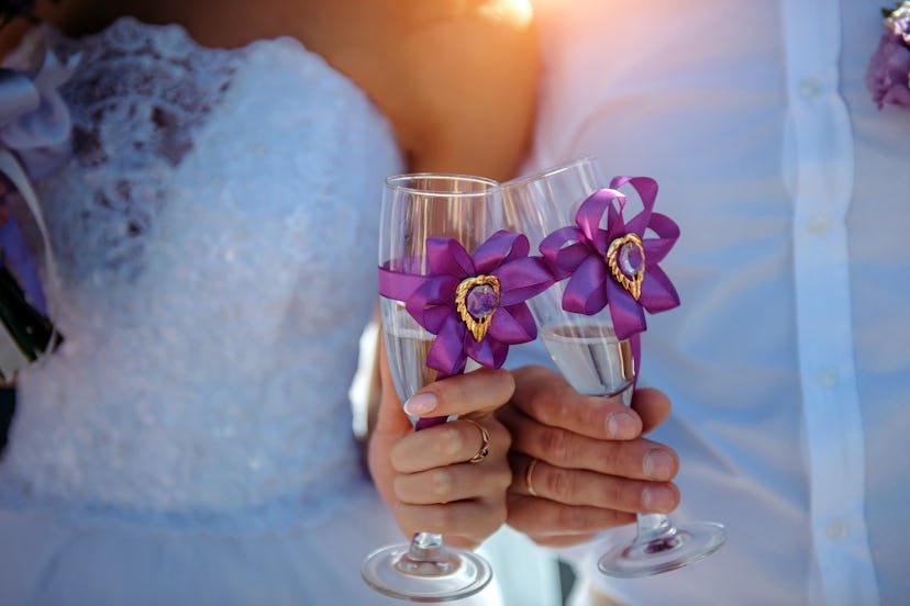 Bride and groom holding glasses of sparkling water in their hands, close-up. If you're not drinking ...