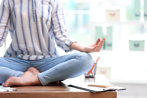 Woman meditating on table in office during break, closeup with space for text. Zen yoga