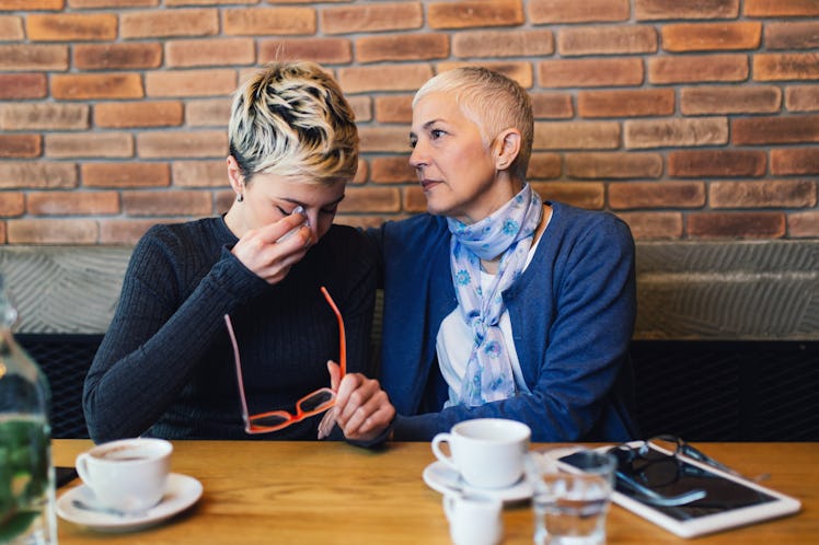 Sad and unhappy daughter sitting in cafe bar or restaurant with her mother and talking.