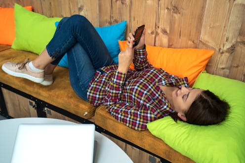 Successful young business womanat lying and talking on mobile phone and scrolling her social media...