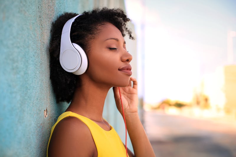 Pretty girl listening music with her headphones in the street