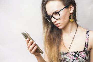 Surprised sad young woman looking in phone