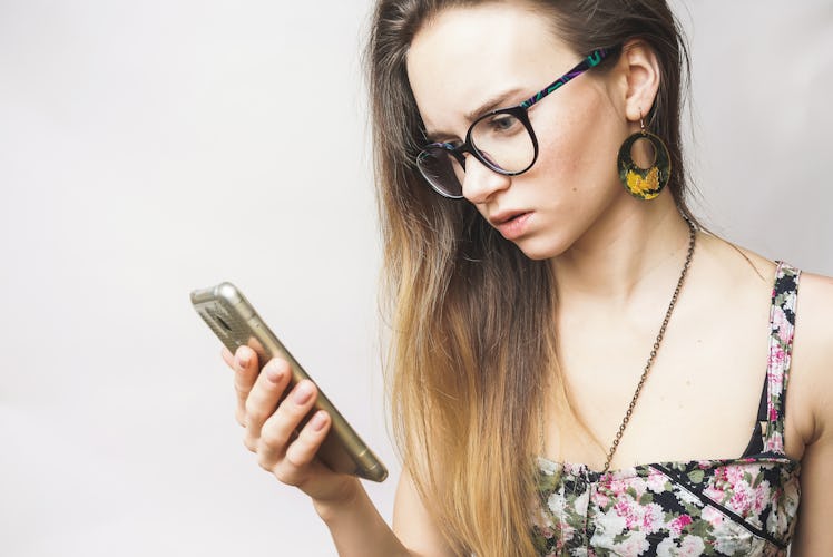 Surprised sad young woman looking in phone