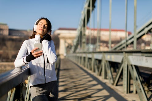 Woman on the bridge making a pause and listen music after the exercise