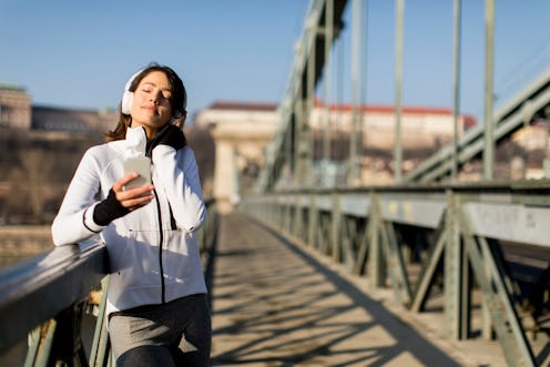 Woman on the bridge making a pause  and listen music after the exercise