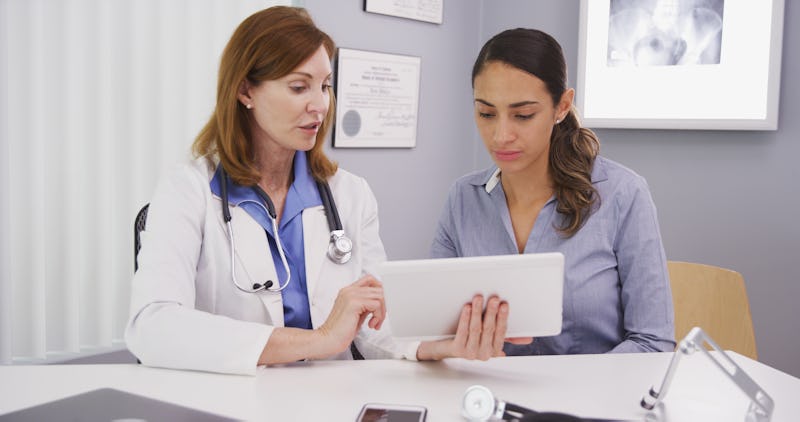 Senior medical physician using tablet to share lab results with young patient