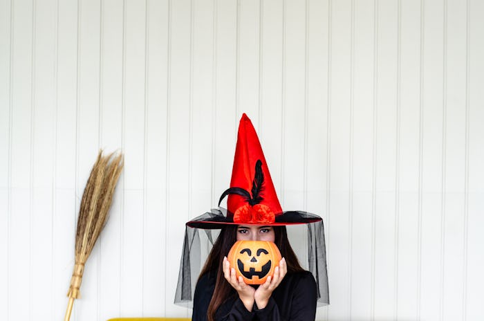 Halloween Witch with a magic Pumpkin ,  Beautiful young woman in witches hat and costume