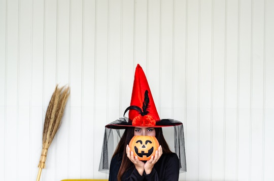 Halloween Witch with a magic Pumpkin ,  Beautiful young woman in witches hat and costume