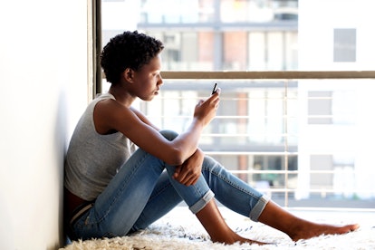 Side portrait of african american female using mobile phone by window at home