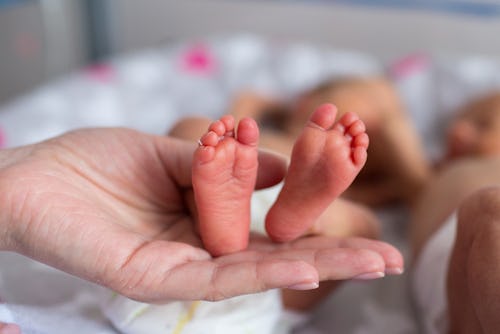 An adult's hand holding a premature baby's feet