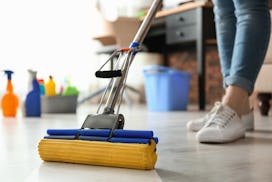 Woman cleaning floor with mop in living room for flu season
