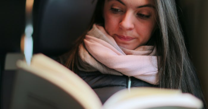 Woman reading book while commuting by train