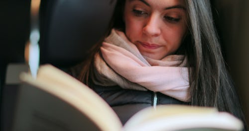 Woman reading book while commuting by train