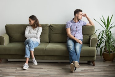 Husband and wife sitting on different sides of couch not looking at each other and not talking, bein...
