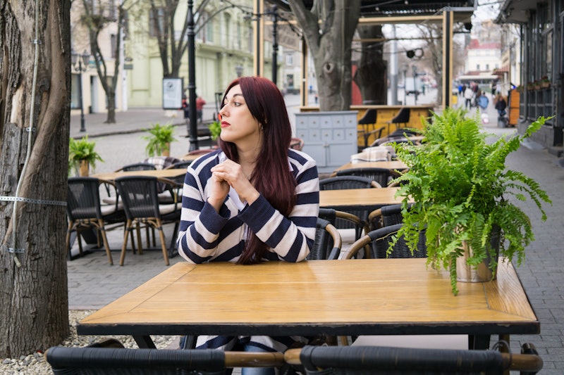 Young lady with long hair sitting alone in cafe